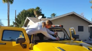 Up To $450 Cash Back | Windshield Replacement Mesa 76 Technician trimming old urethane adhesive from the windshield frame during a Hummer H3 windshield replacement at a customer's home in Mesa, Arizona.